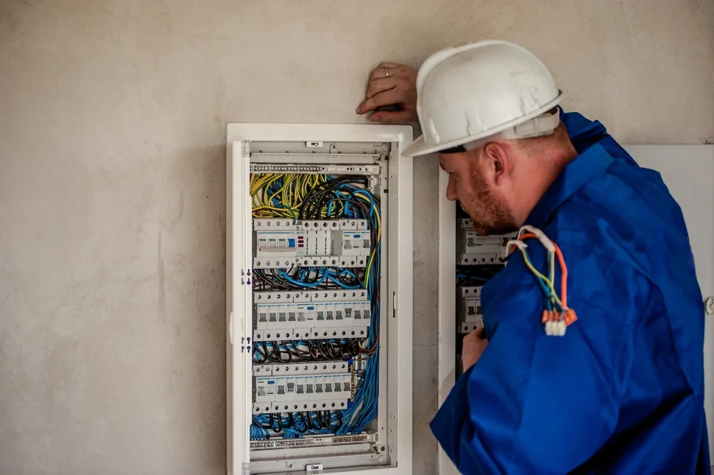 a man in a hard hat looking at a box with wires