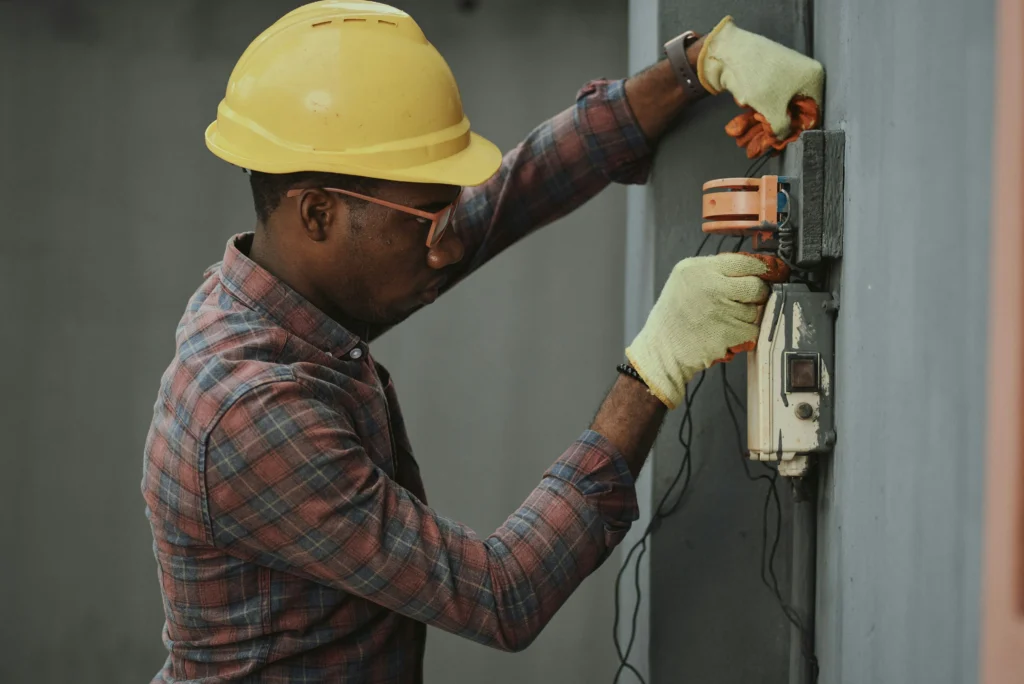 a man wearing a hard hat and gloves working on a power supply